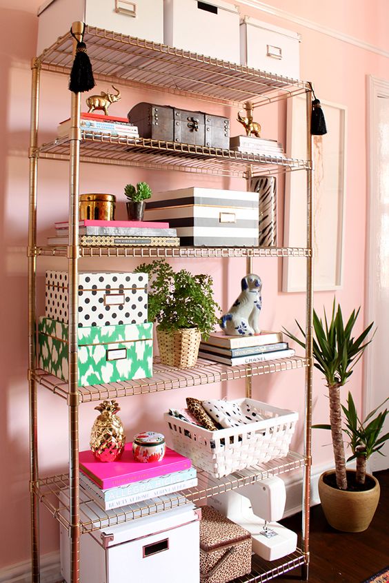 gold wire shelf in a pink room holding feminine office supplies